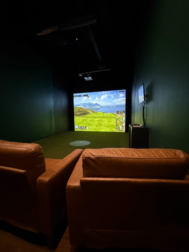 A Chip Shots simulator bay lit for evening play